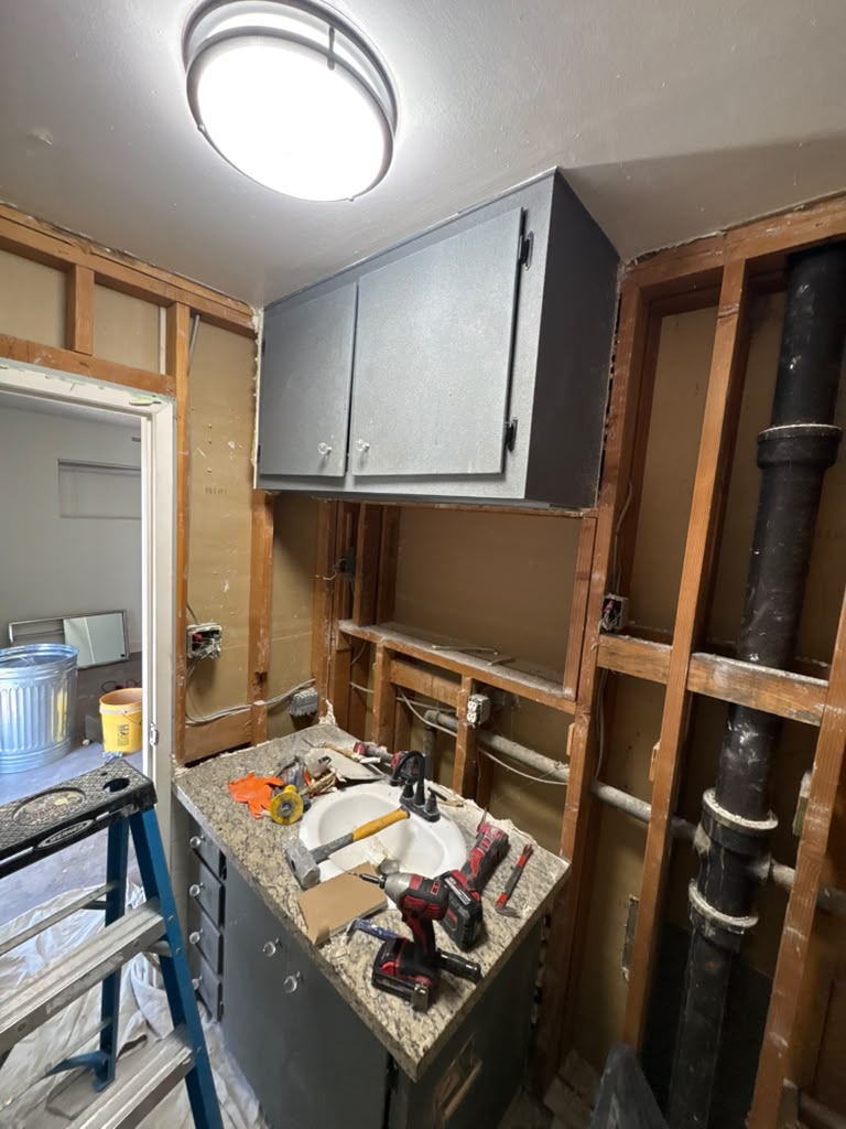 Bathroom opened to the studs with old cast-iron drain stack exposed during a Las Vegas remodel